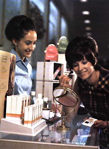 1969 Du Barry make-up counter with a woman is trying on Playthings makeup